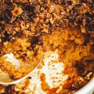 Sweet potato soufflé in a casserole dish with a silver serving spoon.