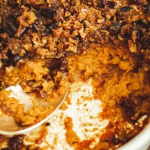 Sweet potato soufflé in a casserole dish with a silver serving spoon.