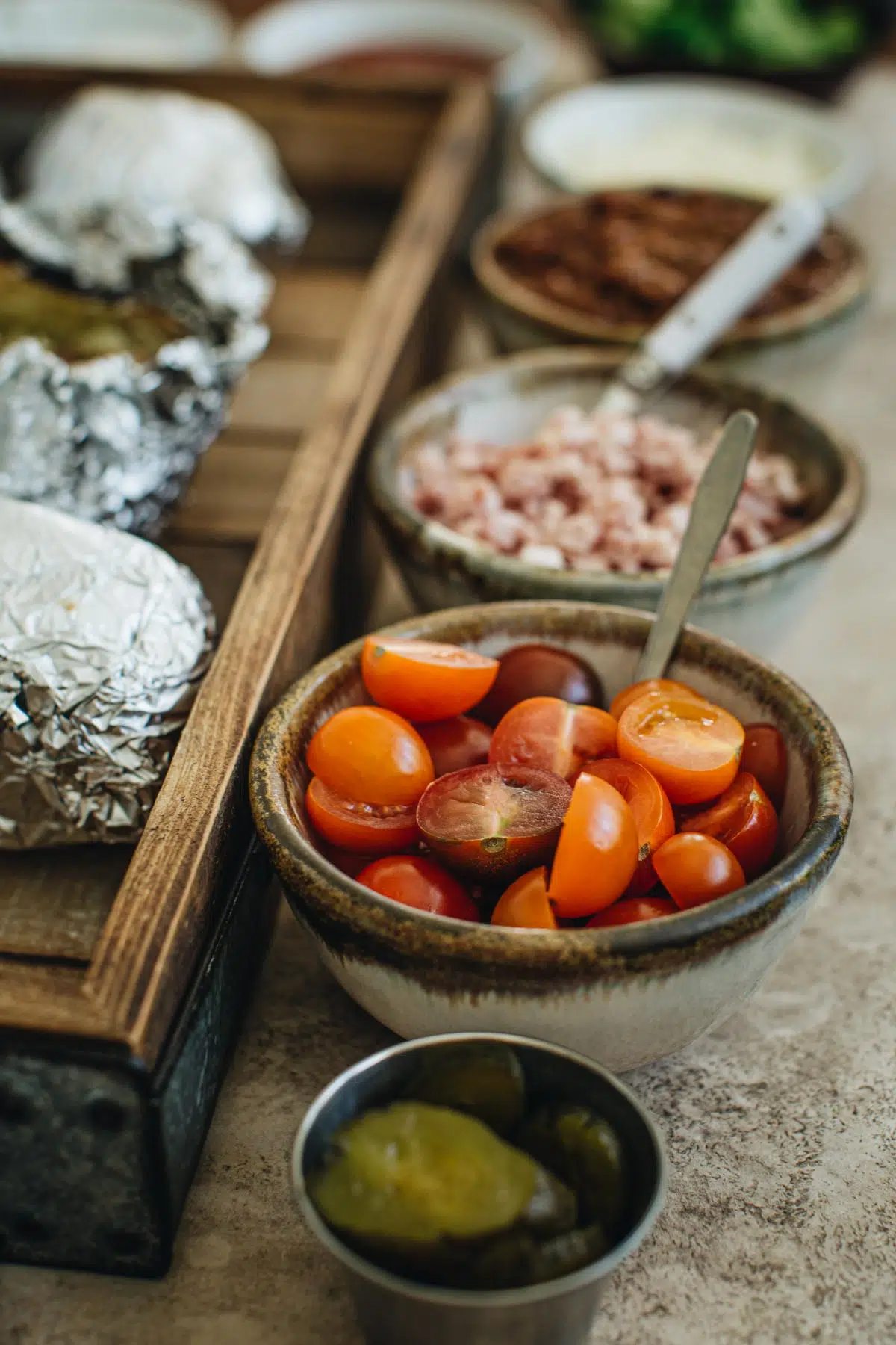 Baked potato bar ideas for toppings in different bowls with mini serving spoons.