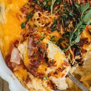 Cheesy potato casserole being scooped up with a silver spoon.