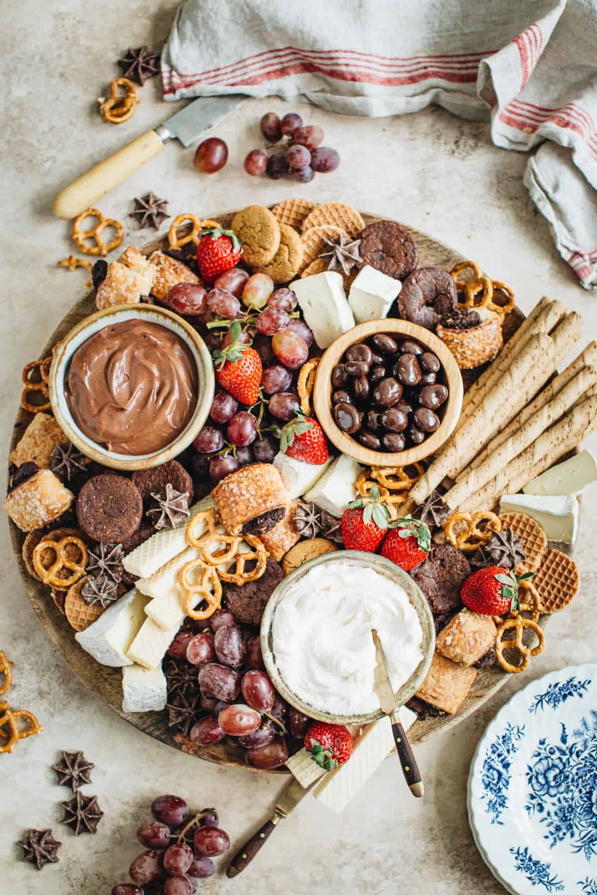 Dessert charcuterie board covered with sweet treats, fruit, and dip in bowls.