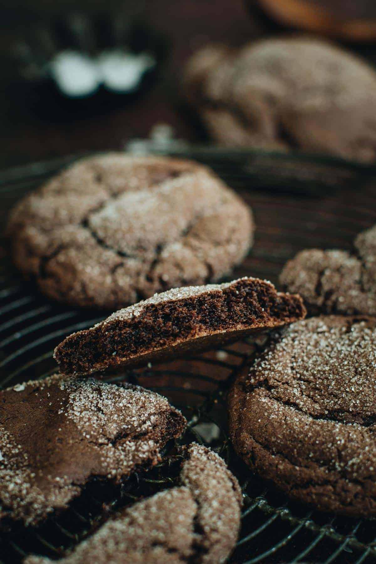 Devil's food cake cookies on a wire rack with one split in half.