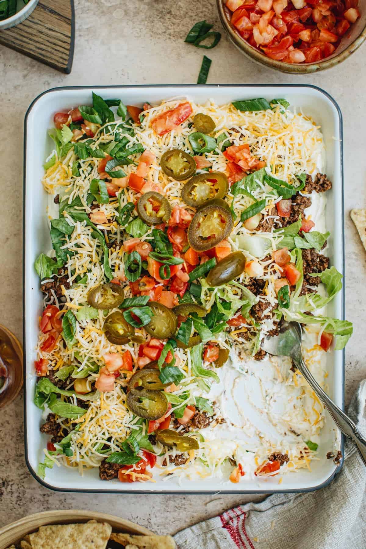 Easy taco dip on a rimmed tray with various toppings.
