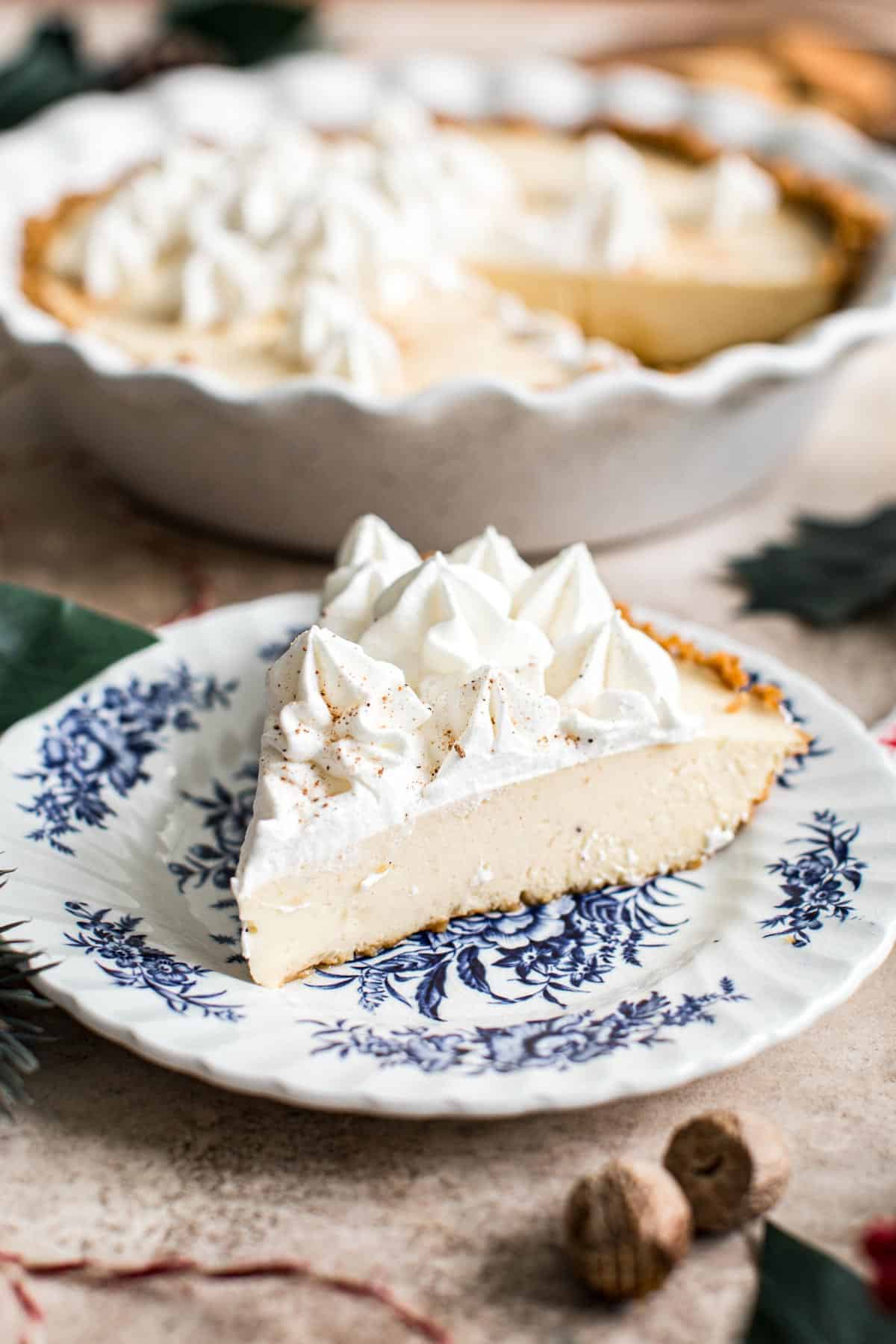 Slice of eggnog pie with gingersnap crust topped with whipped cream.