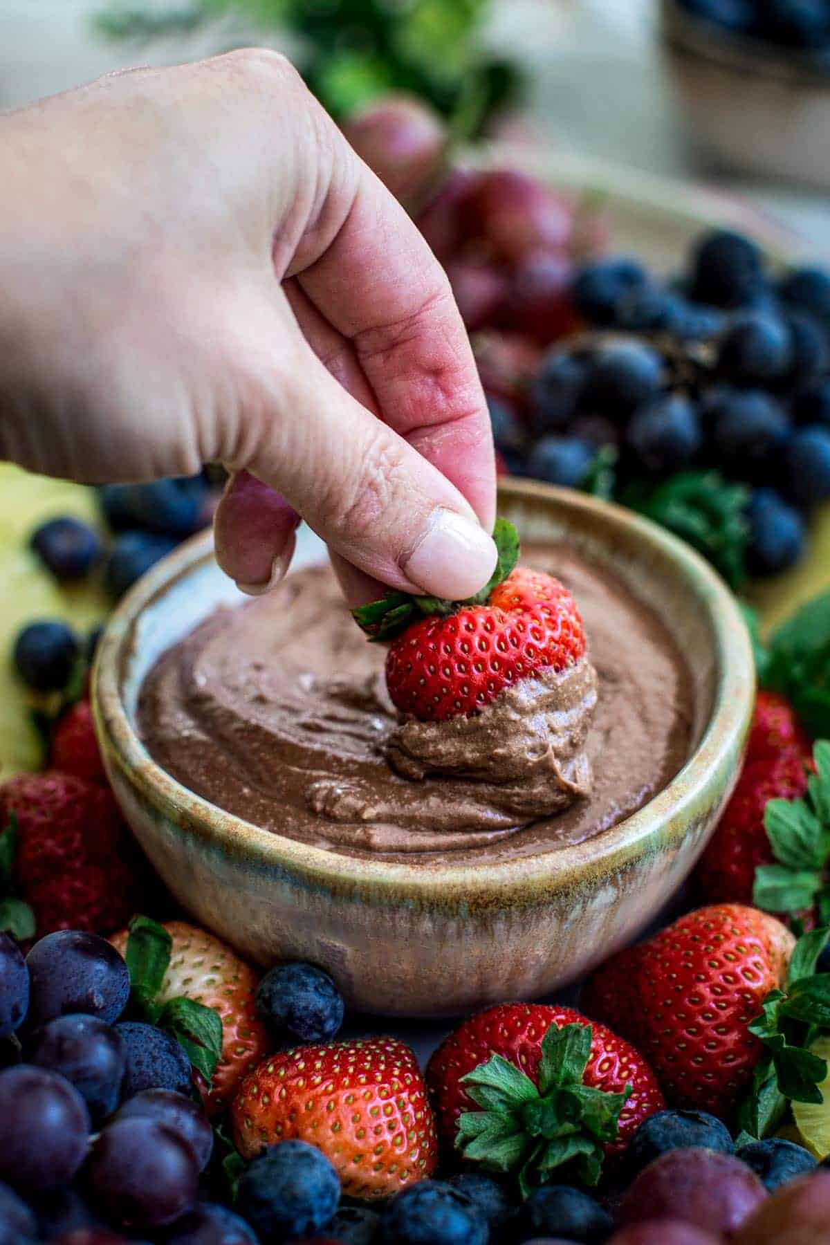Strawberry dipping into chocolate fruit dip.