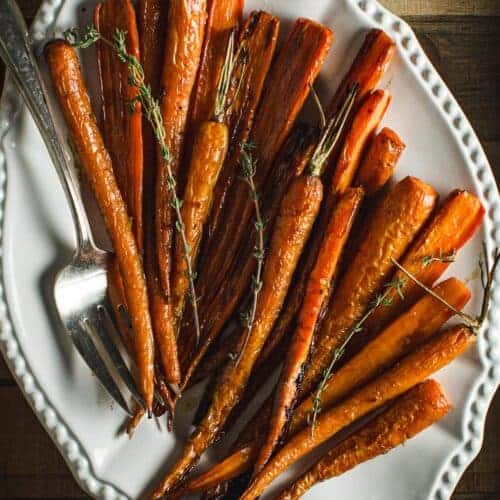 Honey glazed roasted carrots on a white platter.