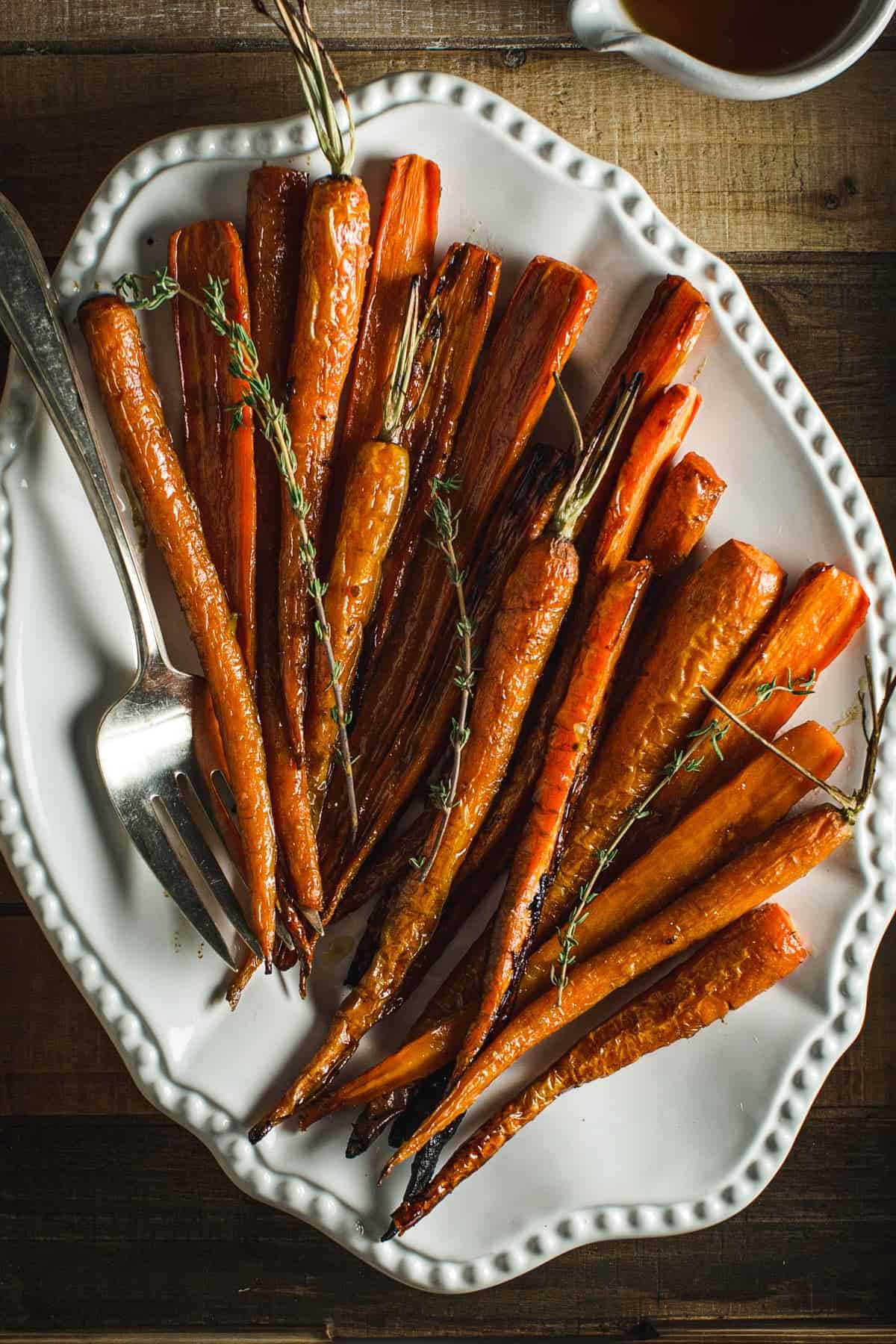 Honey glazed roasted carrots on a white platter.
