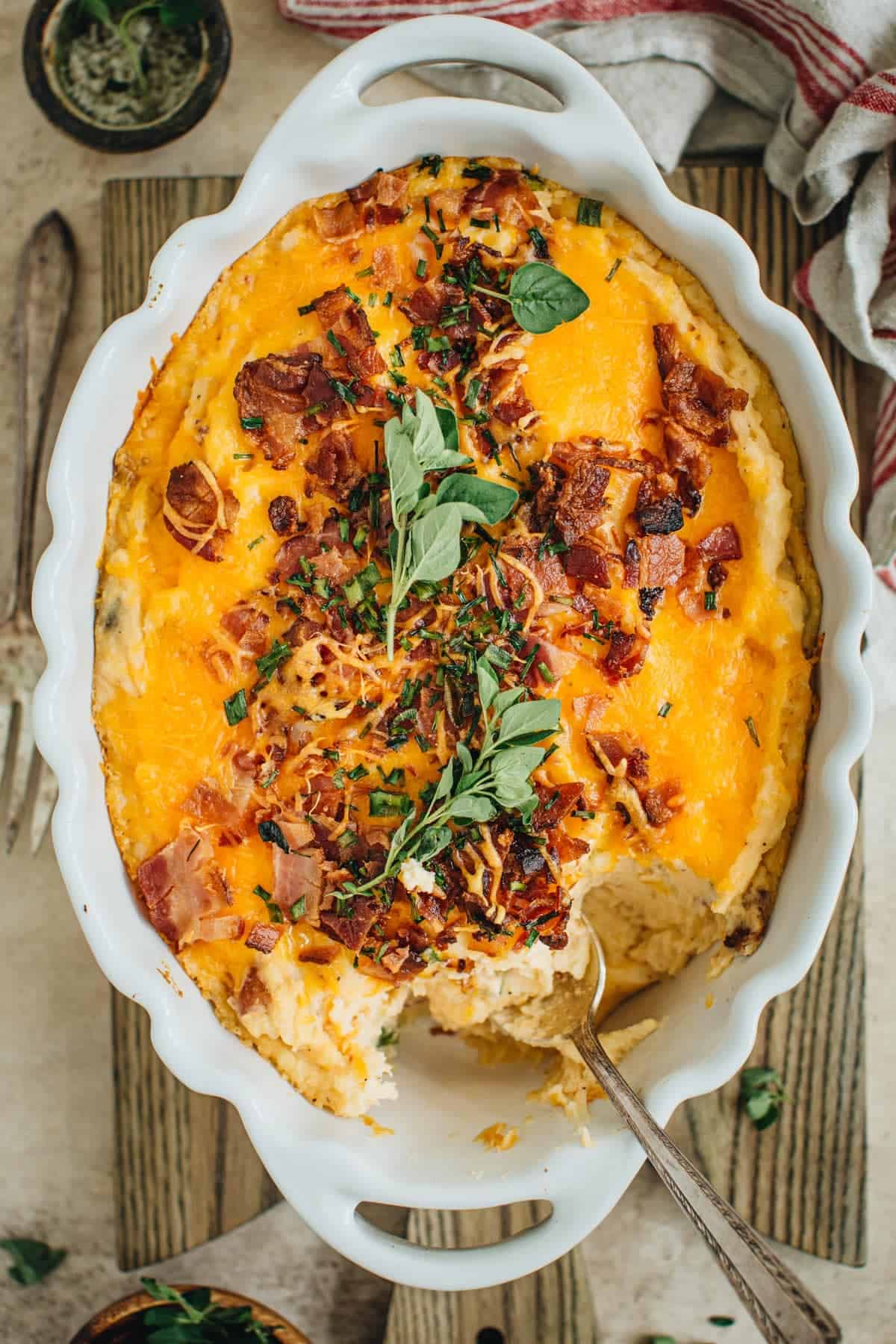 Loaded potato casserole with a serving spoon scooping some out.