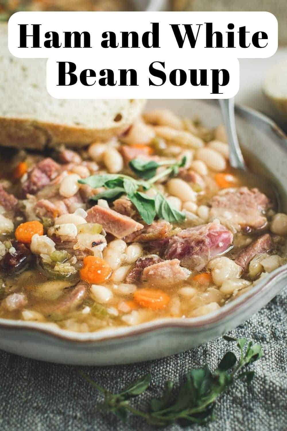 White bean soup with ham in a bowl topped with fresh oregano.