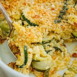 Zucchini casserole with a silver serving spoon scooping up casserole.