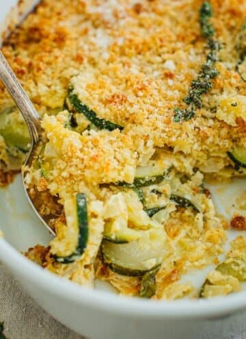 Zucchini casserole with a silver serving spoon scooping up casserole.