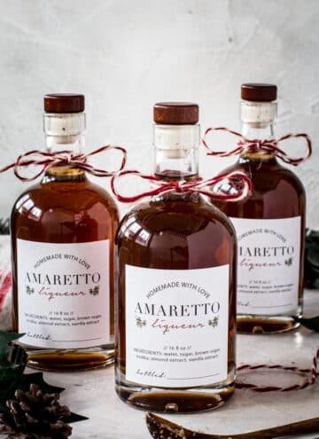 Bottles of homemade amaretto with homemade labels and baker's twine tied around the bottle neck.