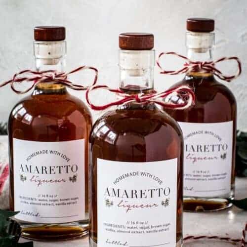 Bottles of homemade amaretto with homemade labels and baker's twine tied around the bottle neck.