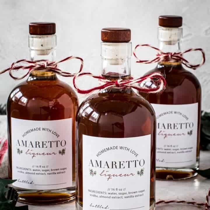 Bottles of homemade amaretto with homemade labels and baker's twine tied around the bottle neck.
