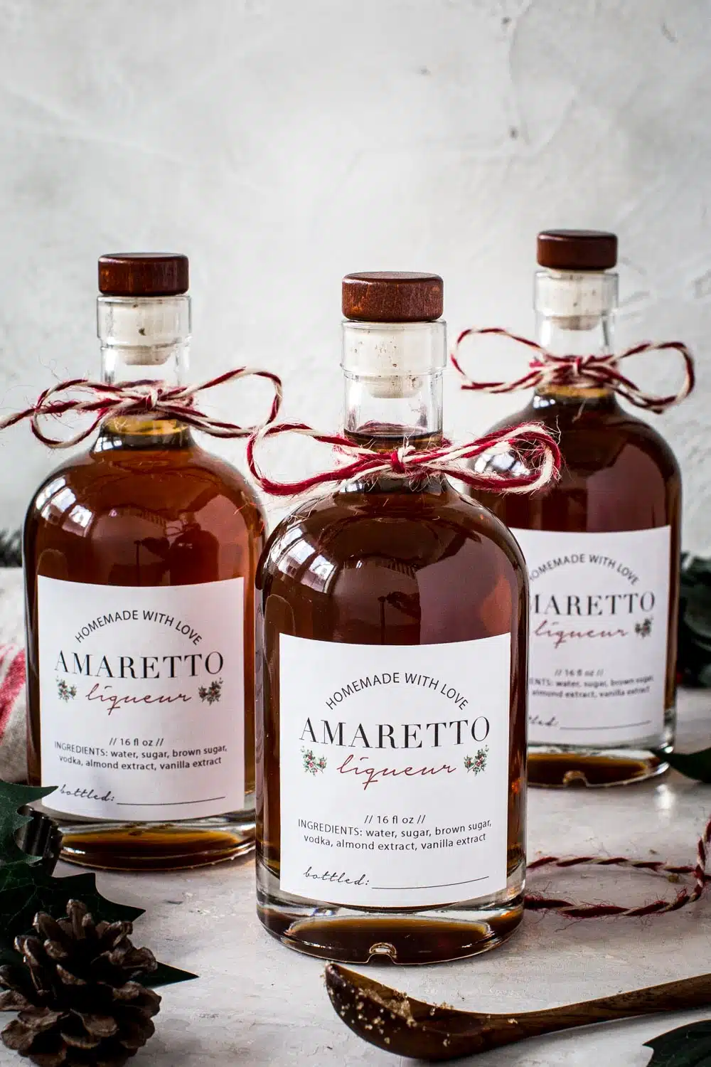 Bottles of homemade amaretto with homemade labels and baker's twine tied around the bottle neck.