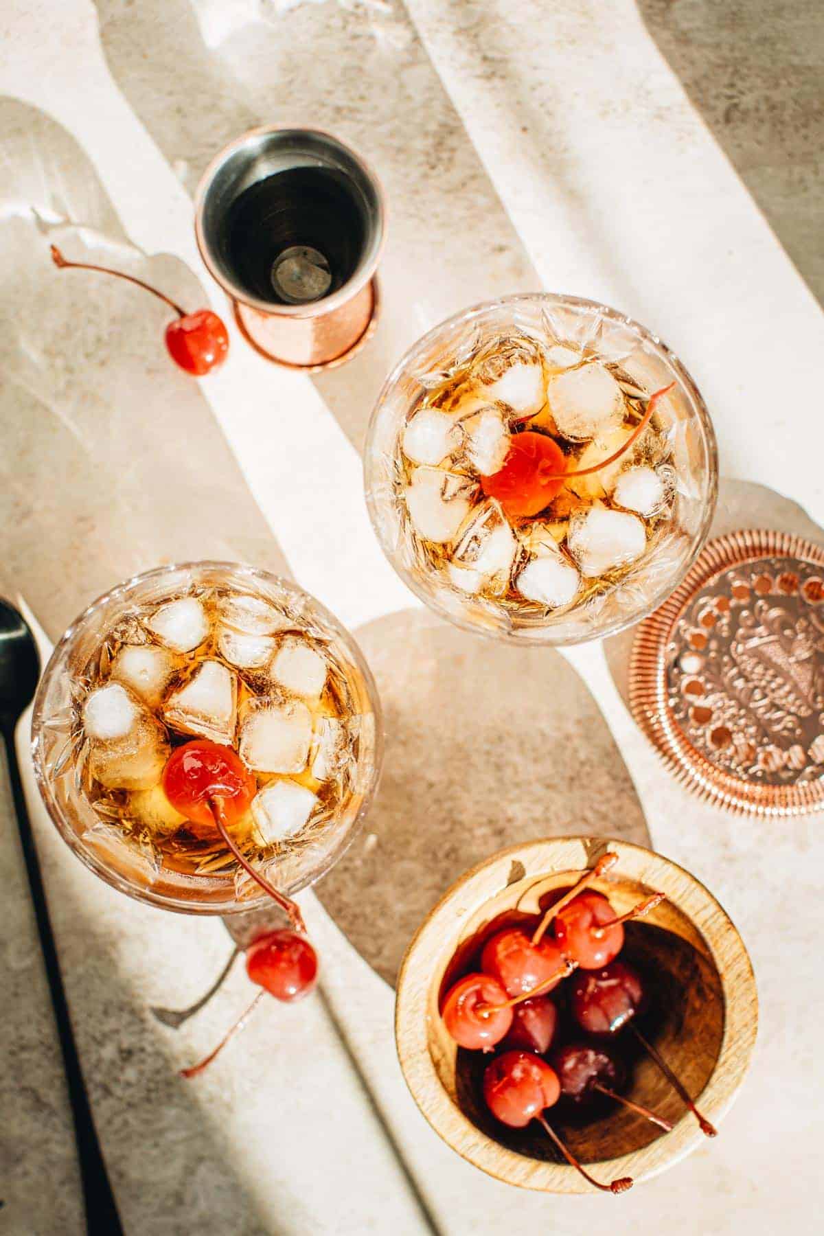 Black Russian cocktails in glasses with cherries for garnish.