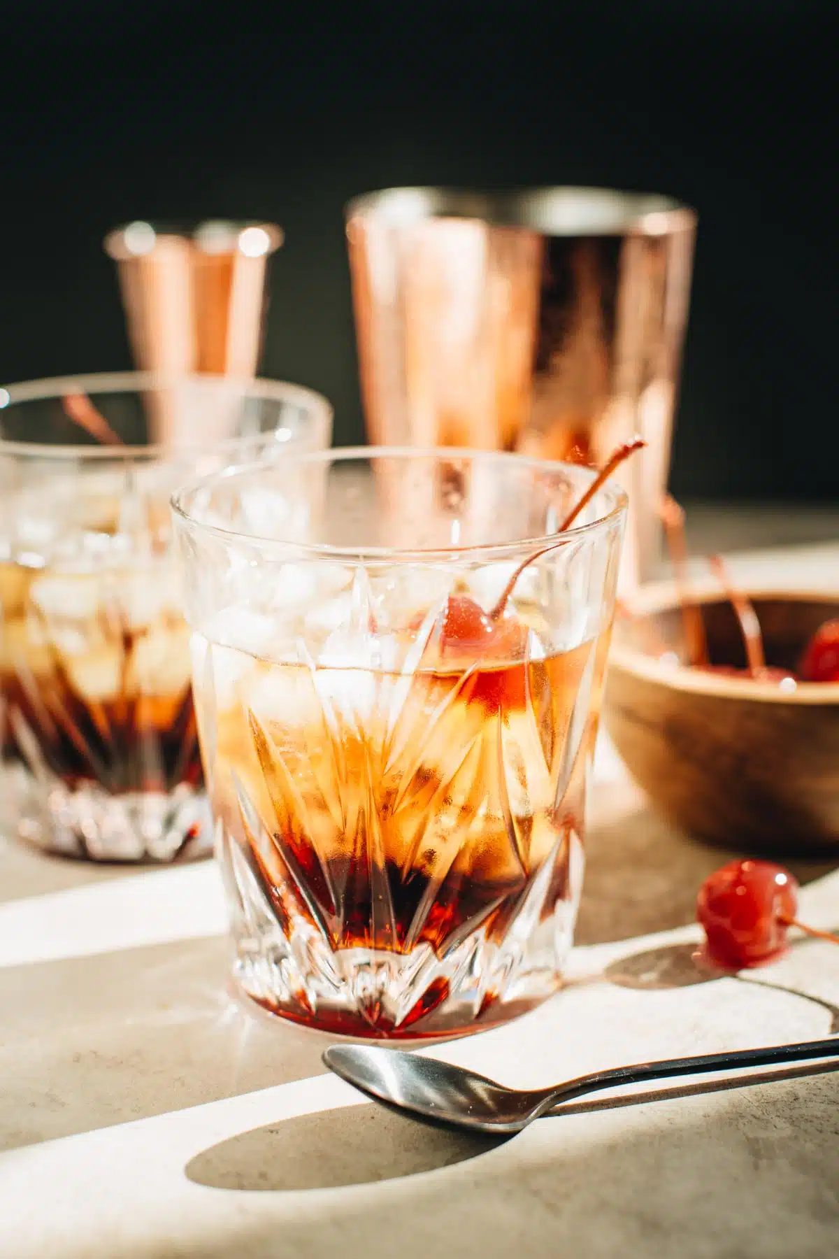 Black Russian cocktail in a rocks glass with a cherry garnish.