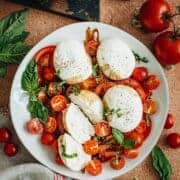 Burrata caprese topped with fresh basil in a white serving bowl.
