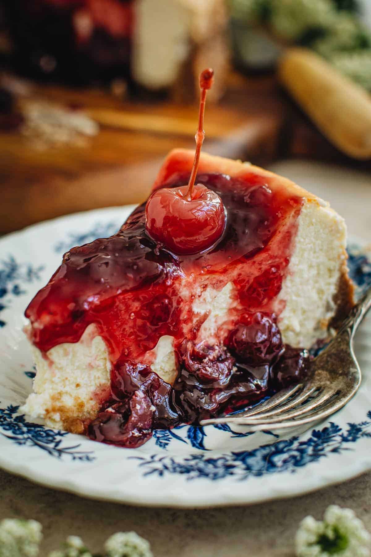 Cherry cheesecake on a blue and white dessert plate with a fork.