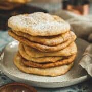 Indian fry bread stacked on a plate and dusted with powdered sugar.