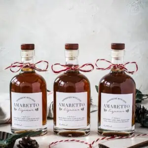 Three bottles of homemade amaretto with personalized labels.