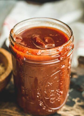 Carolina bbq sauce in a Mason jar with sauce dripping down the side.