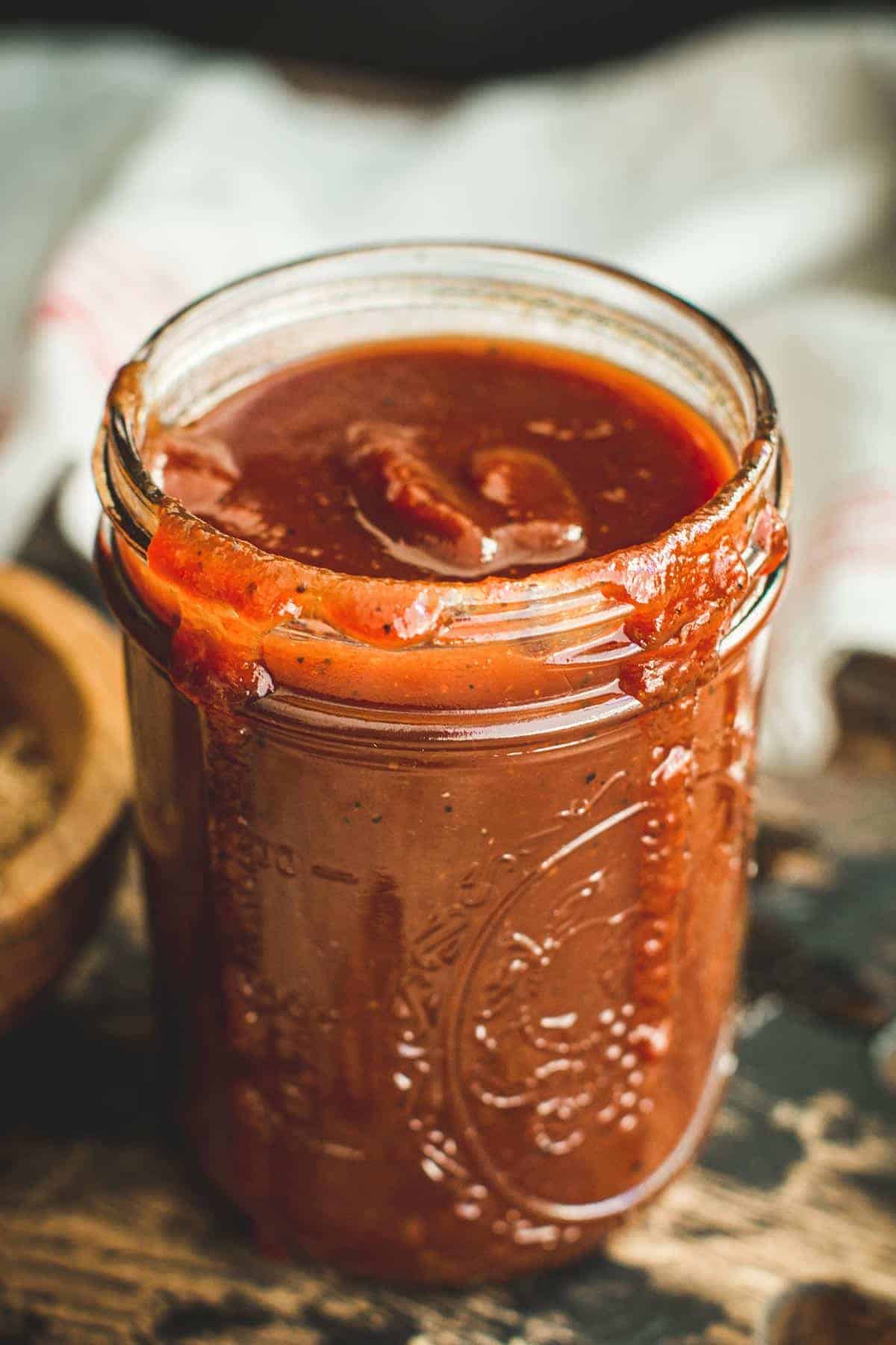 Carolina bbq sauce in a Mason jar with sauce dripping down the side.