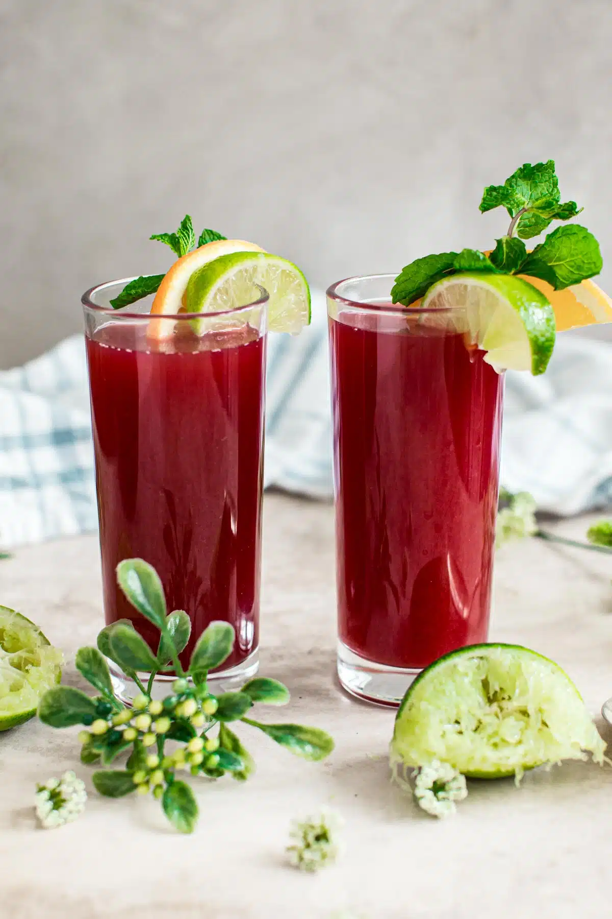 Fruit punch drink in tall glasses with orange and lime wedges on the rim.