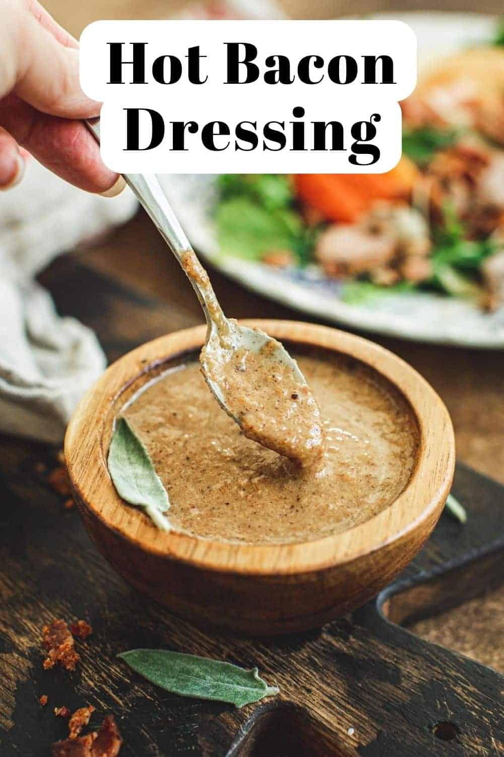 Hot bacon dressing recipe in a wooden bowl with a silver serving spoon.
