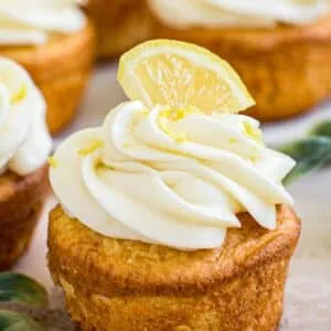 Cupcake topped with frosting, lemon zest, and a small lemon wedge.