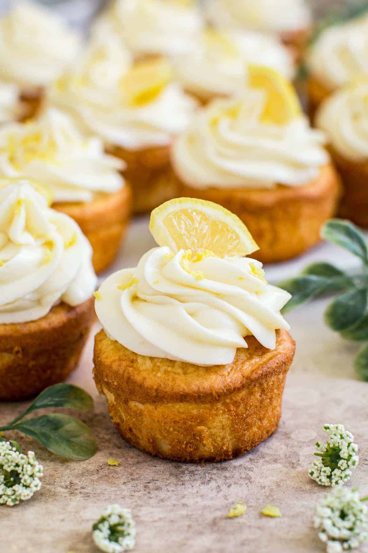 Cupcake topped with lemon cream cheese frosting, lemon zest, and a lemon wedge.