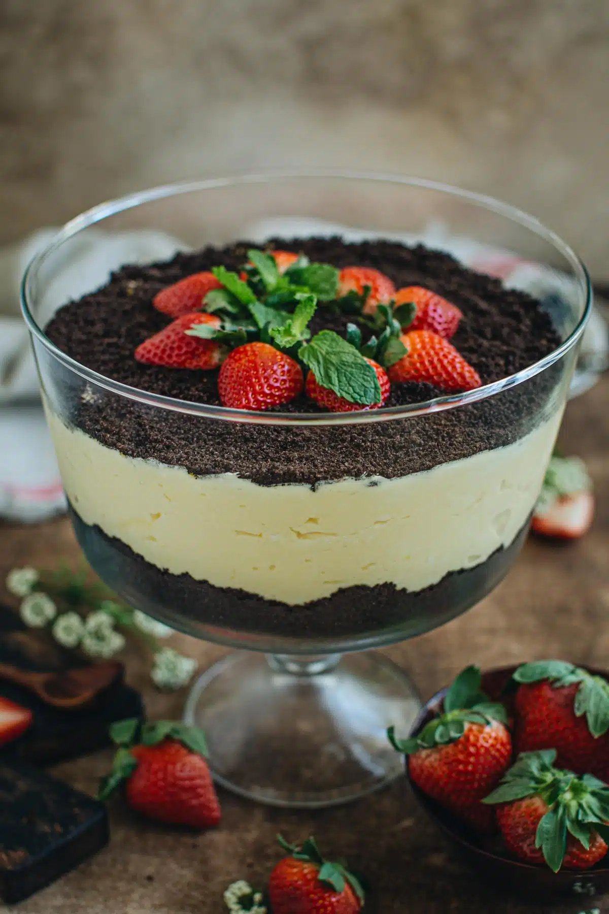 Oreo dirt cake in a trifle bowl topped with strawberries.