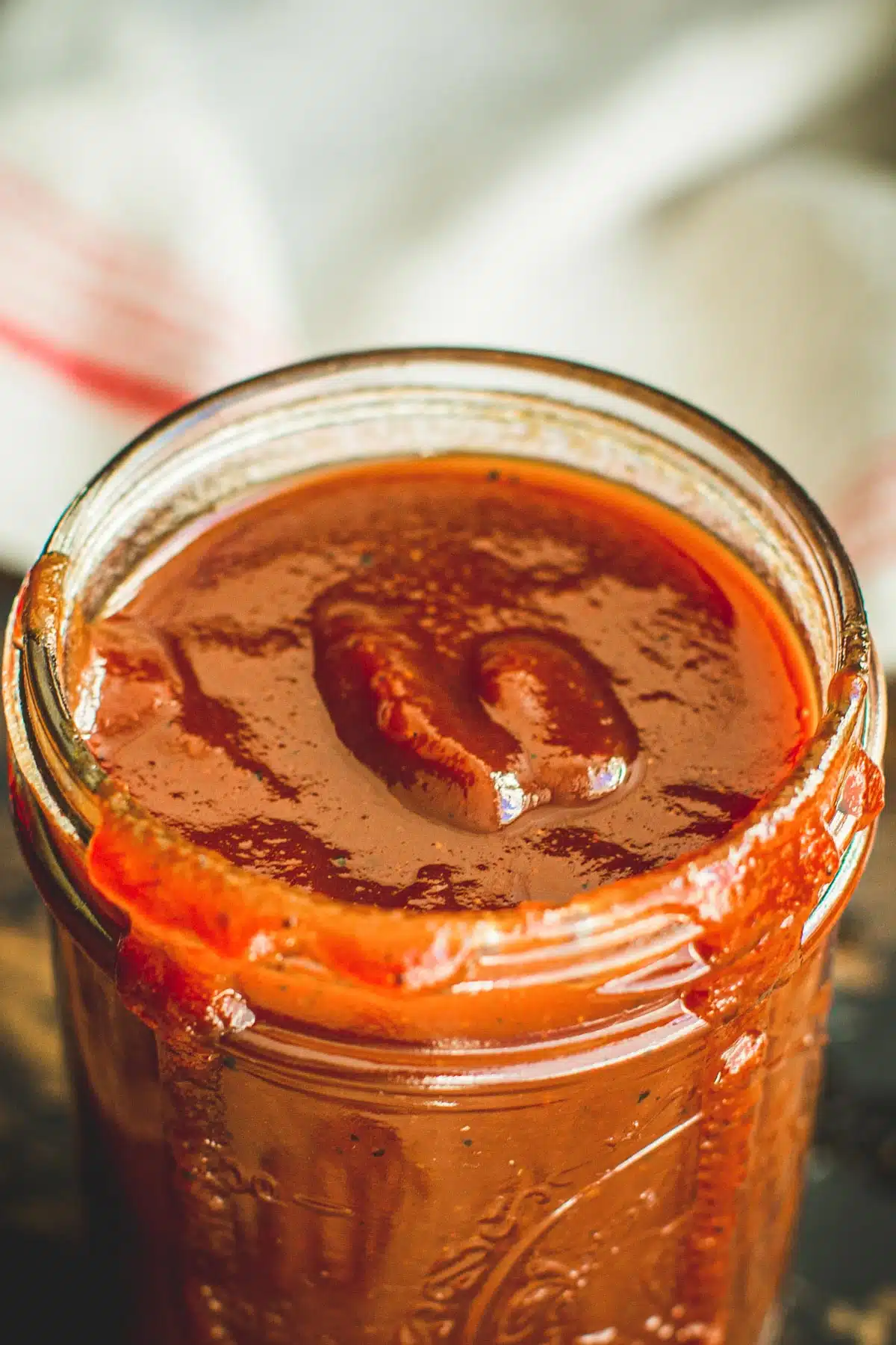 Carolina vinegar-based bbq sauce in a wide-mouth Mason jar with sauce dripping down the side.