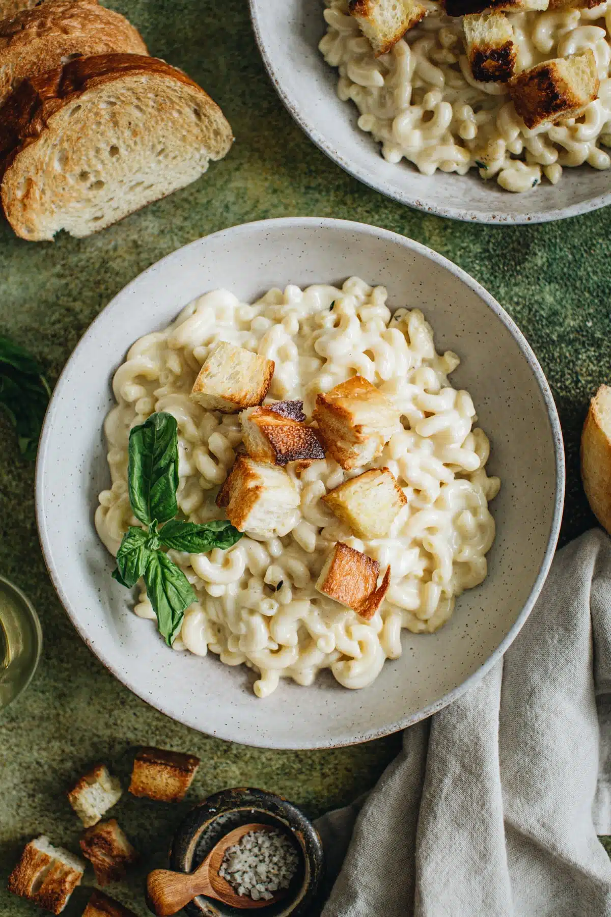 Mac and cheese in a bowl topped with homemade croutons and basil.