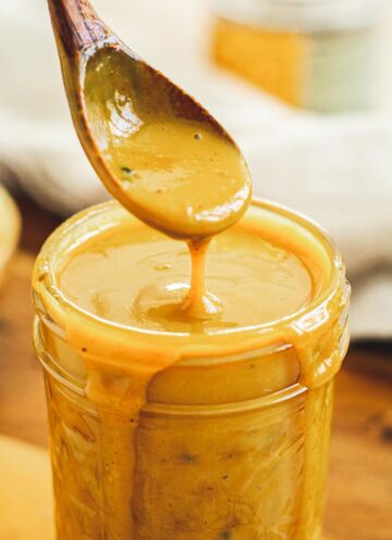 Carolina gold bbq sauce dripping off a wooden spoon.