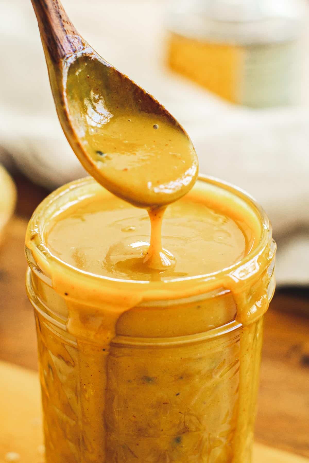 Carolina gold bbq sauce dripping off a wooden spoon.