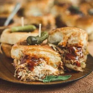 Pulled pork sliders on a wooden plate.