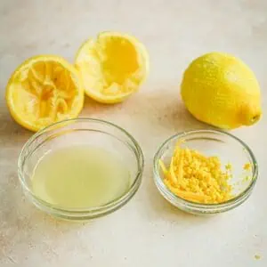 Lemon juice in a bowl next to lemon zest in a bowl.
