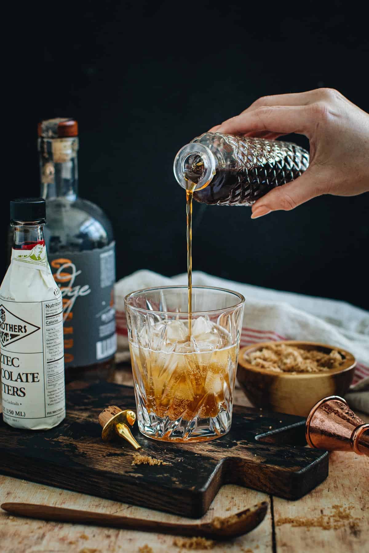 Brown sugar syrup pouring into a cocktail glass with ice.