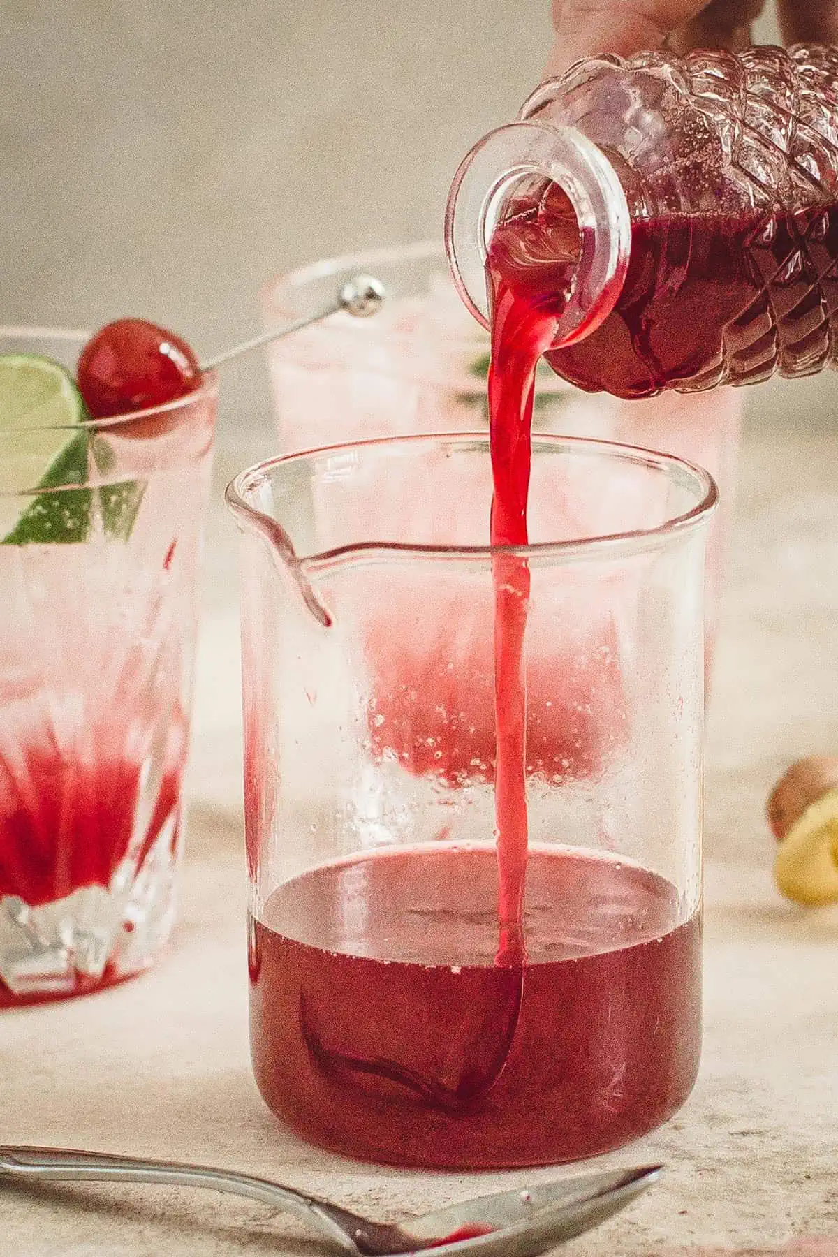 Homemade grenadine syrup pouring into a glass cup.