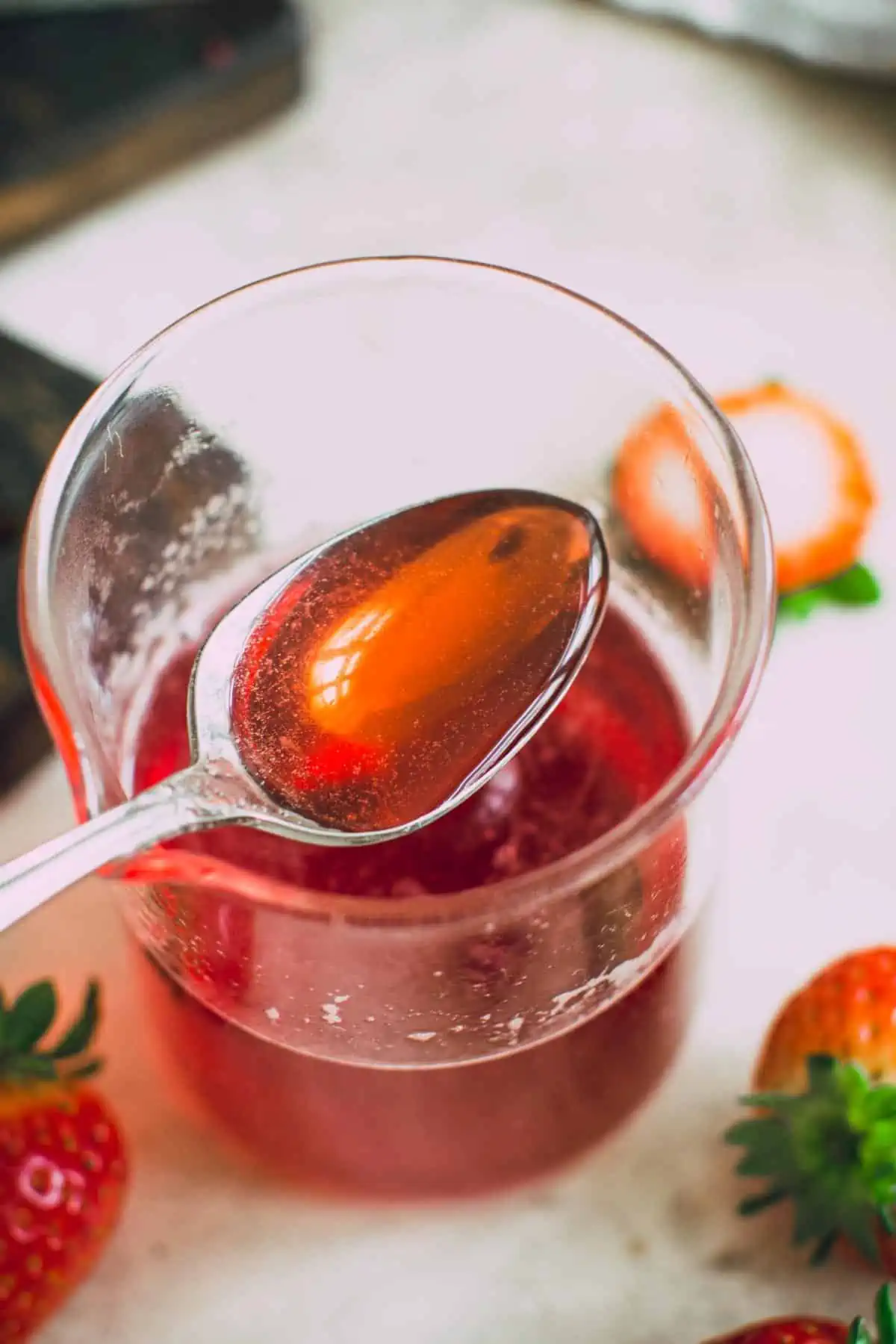 Spoon filled with strawberry syrup.