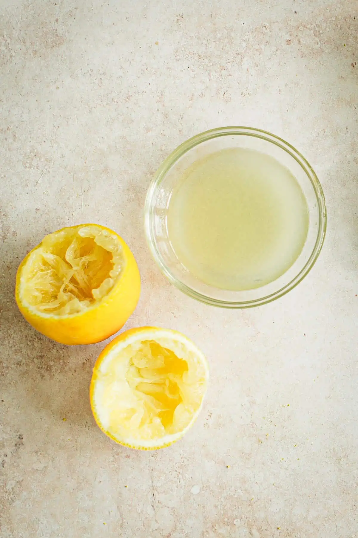 Lemon juice in a bowl with lemon halves next to it.