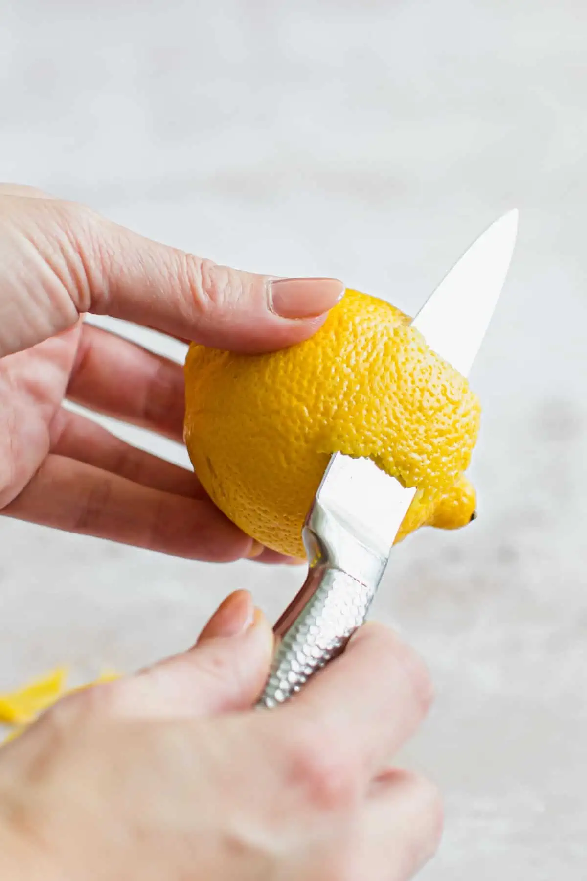 Using a knife to zest a lemon.