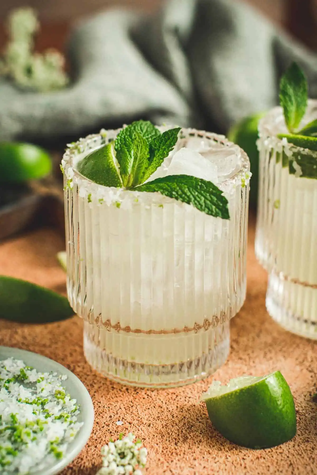 Margarita on the rock with a mint leaf and lime wedge.