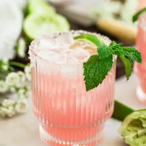 Pink margarita with mint leaves and a lime wedge.