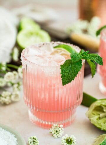 Pink margarita with mint leaves and a lime wedge.