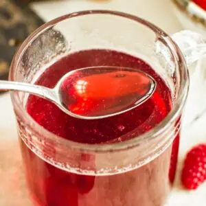 Raspberry simple syrup on a spoon.