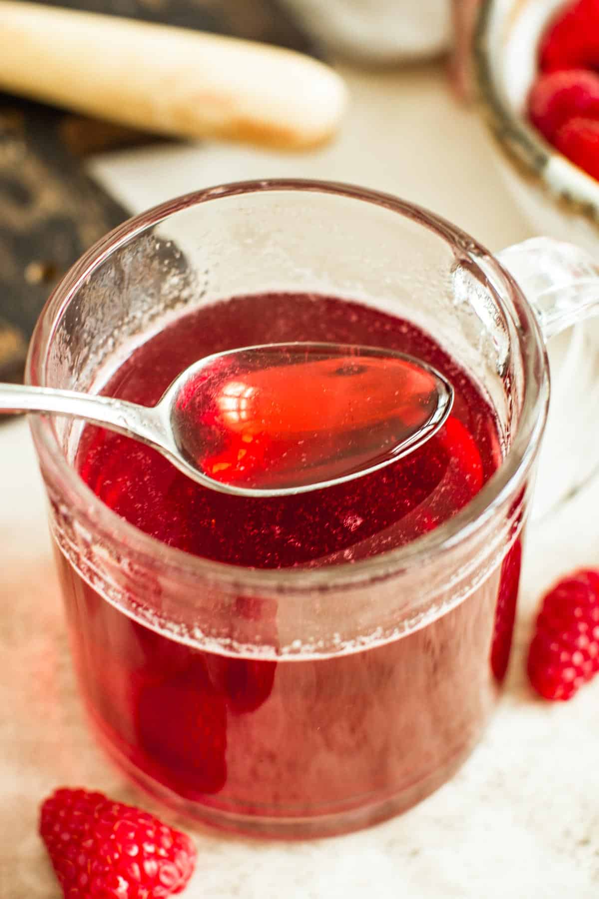 Raspberry simple syrup on a spoon.