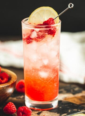 Raspberry Collins with a fresh raspberry and lemon wedge for garnish.
