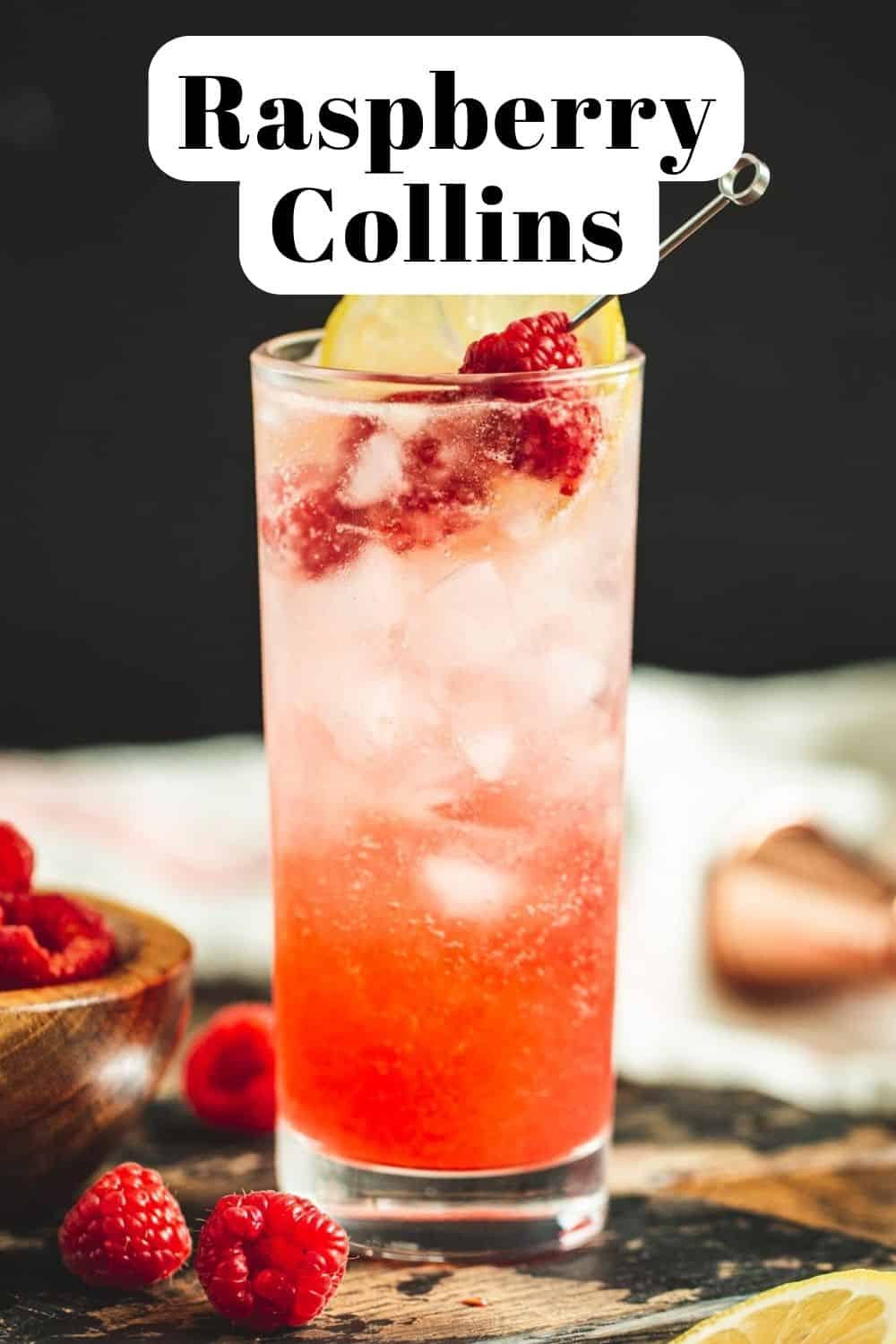Raspberry collins topped with fresh raspberries and a lemon slice.